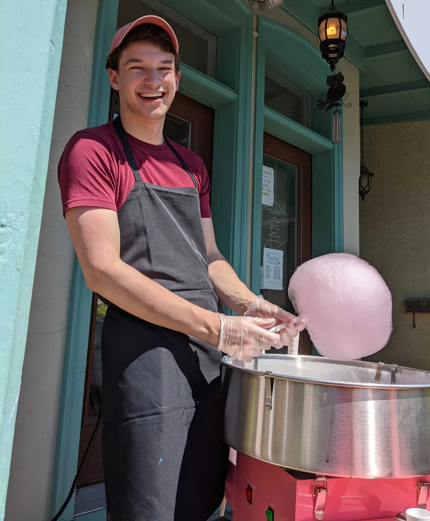 A smiling vendor makes pink cotton candy outside a Conshohocken storefront.